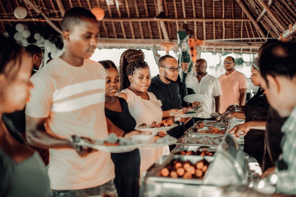 Group of African adults enjoying a festive buffet indoors with a lively atmosphere.